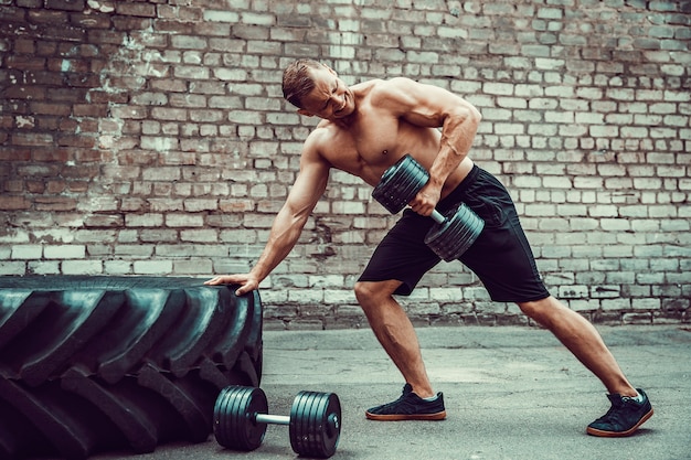 Athletic man working out with a dumbbell. Strength and motivation. Exercise for the muscles of the back