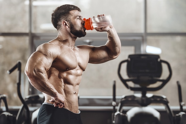 athletic men drinking water in the gym