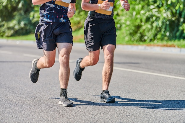 Athletic men jogging in sportswear on city road