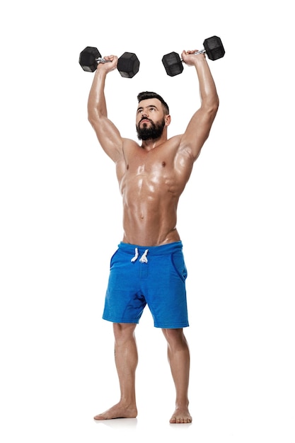 Athletic muscular man doing exercises with dumbbells. Strong bodybuilder with naked torso on white background