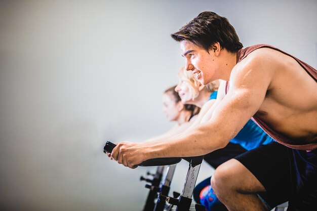 Photo athletic people cycling in gym