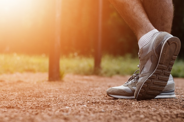 Athletic runner preparing for morning workout in the park, lens flare