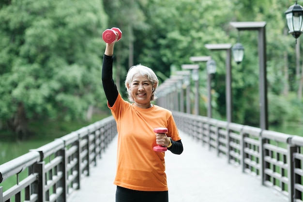 Athletic Senior woman lifts dumbbells while doing fitness