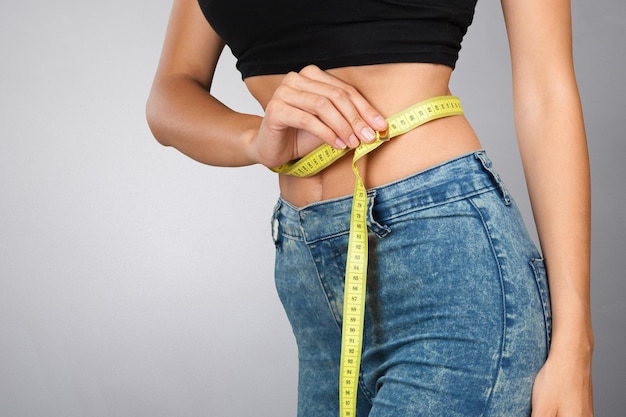 Athletic slim woman measuring her waist by measure tape