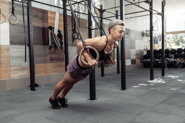 Athletic sport woman exercising with gymnastics rings in modern cross gym