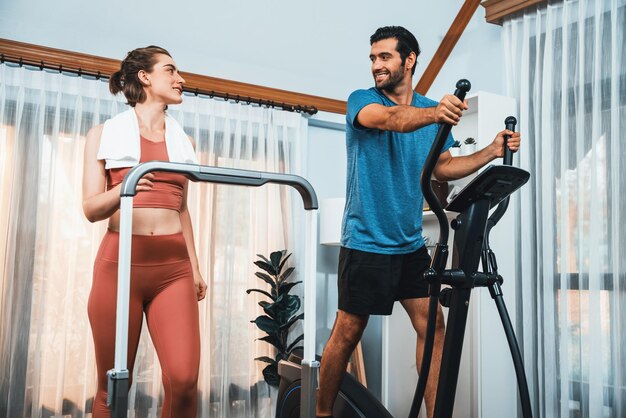 Photo athletic and sporty couple running on elliptical running machine at gaiety home