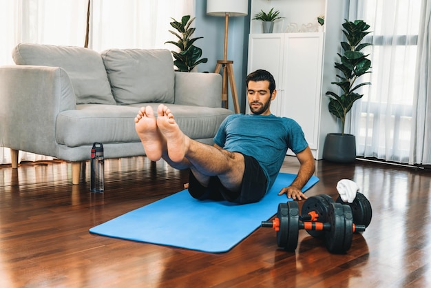 Athletic and sporty man doing crunch on fitness mat at gaiety home