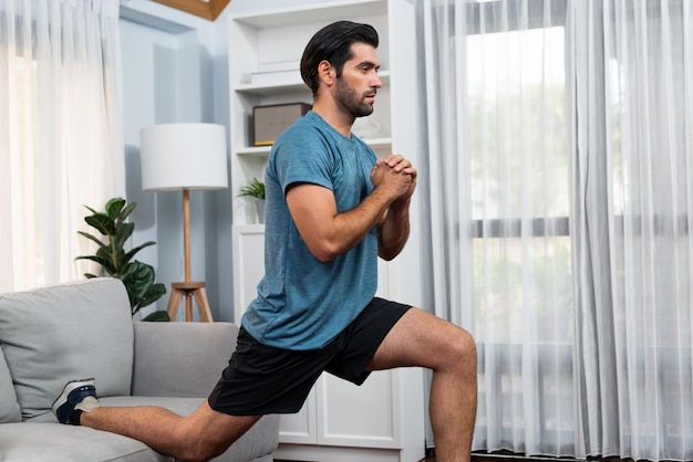 Athletic and sporty man doing squat at gaiety home exercise