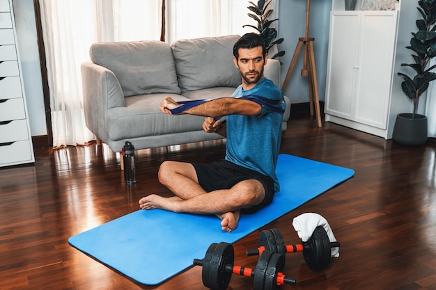 Athletic and sporty man pulling resistance band exercise at gaiety home workout