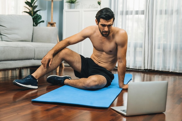 Photo athletic and sporty man resting on fitness mat during online gaiety home