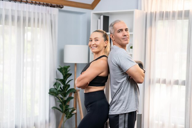 Athletic and sporty senior couple portrait in sportswear with standing posture as home exercise concept healthy fit body lifestyle after retirement clout