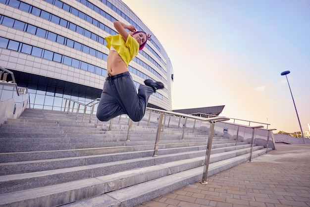 Athletic sporty woman in a yellow T-shirt and dyed pink hair jumped high