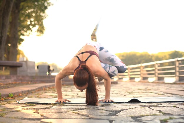 Photo athletic strong woman practicing difficult yoga pose outdoors.