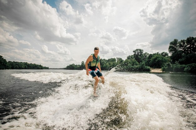 Surfista atletico che guida wakeboard per eseguire le sue abilità professionali