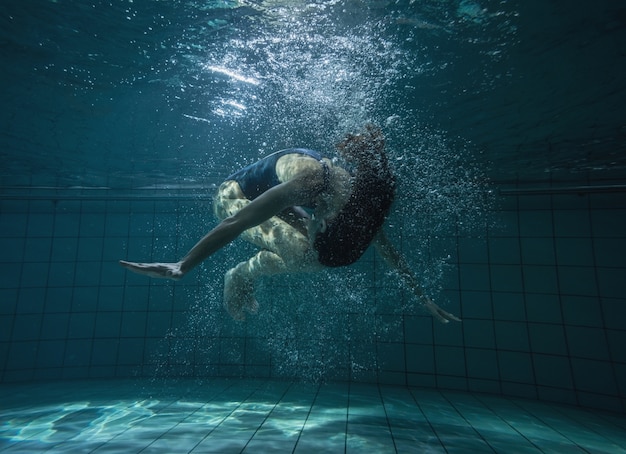 Nuotatore atletico che fa una capriola sott'acqua