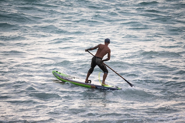 Фото Спортивный серфер плывет с веслом на доске в море stand up paddleboarding