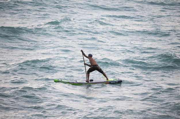 Фото Спортивный серфер плывет с веслом на доске в море stand up paddleboarding