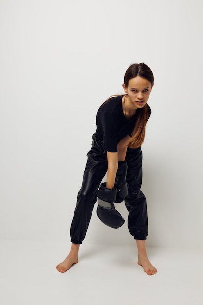 Athletic woman in black sports uniform boxing gloves posing isolated background