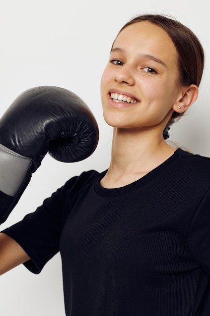 孤立した背景のポーズをとって黒いスポーツユニフォームボクシンググローブの運動の女性