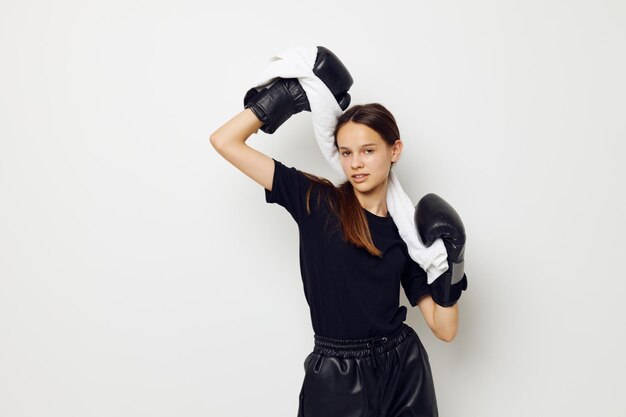 黒のズボンとTシャツの孤立した背景のボクシンググローブでアスリートの女性