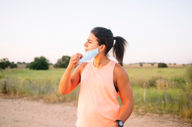 Athletic woman covering her mouth and nose with mask on the street