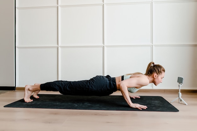 Athletic woman doing physical exercise at home on yoga mat
