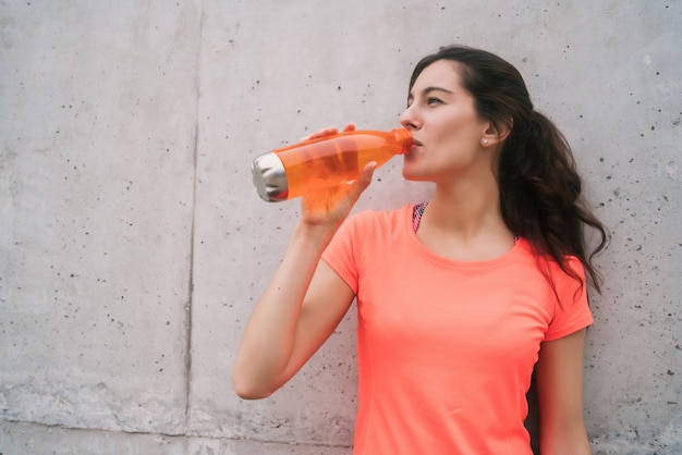 Athletic woman drinking water after training.