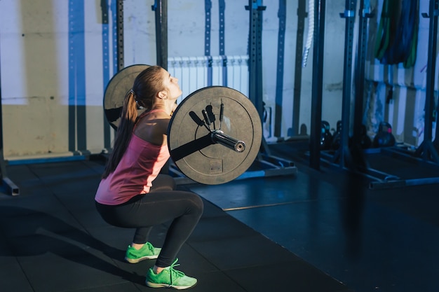 Athletic woman exercising with a barbell in the gym