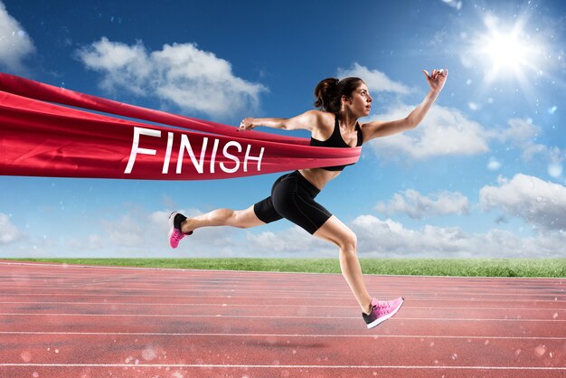 Photo athletic woman goes beyond the red ribbon at the arrival of a race