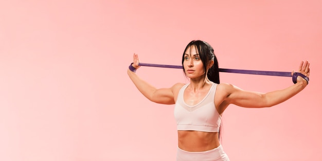 Donna atletica in attrezzatura della palestra che allunga la banda di resistenza