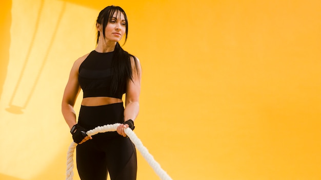 Athletic woman in gym outfit with rope