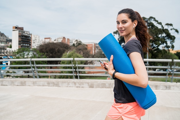 Donna atletica che tiene una stuoia di addestramento.