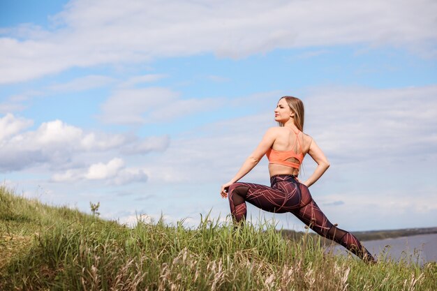 Athletic woman is doing lunge, training outdoors by the nature.
