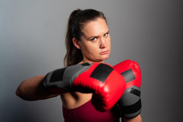 Athletic woman practicing punches in boxing gloves