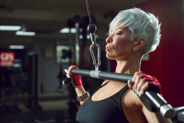 Athletic woman pumping up muscles on the simulator in the fitness room