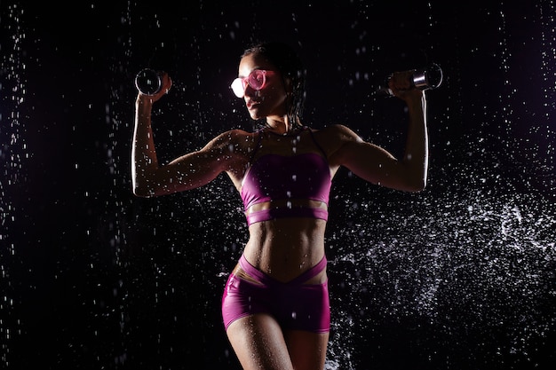 Athletic woman pumping up muscles with dumbbells