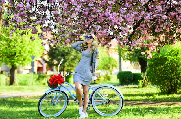 Athletic woman ride retro bicycle Rest and travel Travel by bike Weekend concept Spring holidays Riding bicycle Girl and sakura blossom Cycling Tours Excursion to garden Cherry tree blooming