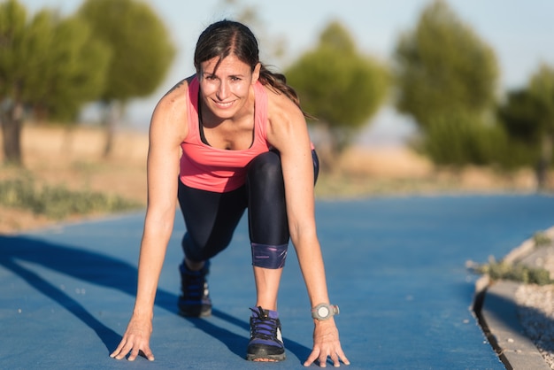 実行を開始する準備をしてランニングトラック上の運動の女性。