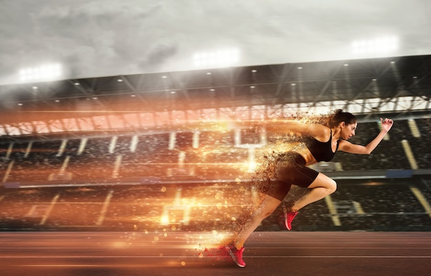 Athletic woman runs in a sport competition with lights trails on the stadium track