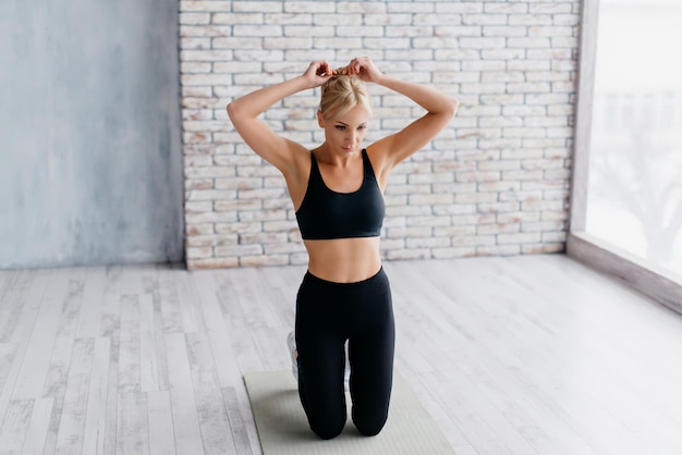 Photo athletic woman sitting on mat in fitness studio