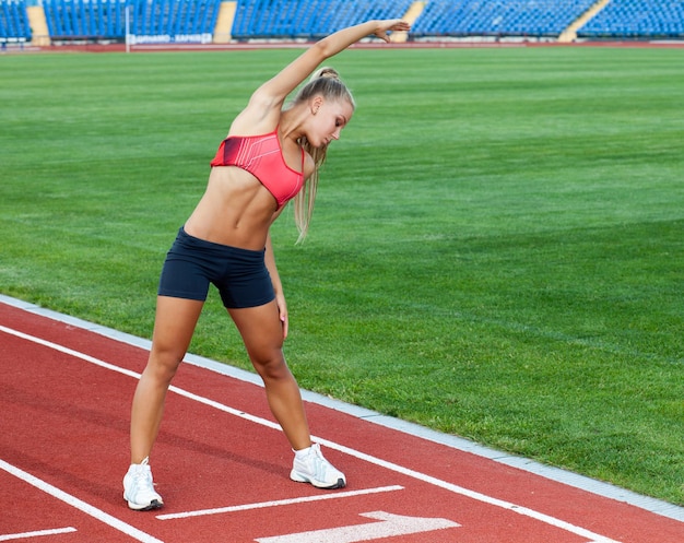 Спортсменка в спортивном костюме делает упражнения перед бегом