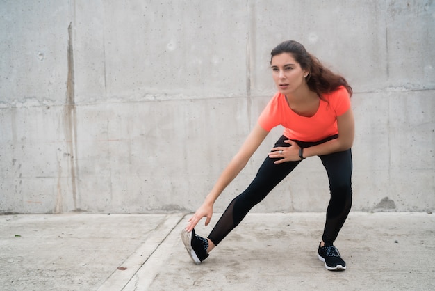 Атлетическая женщина протягивая ноги перед тренировкой