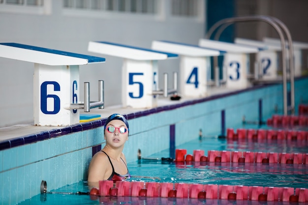 Фото Спортивная (ый) женщина, плавающая в плавательной шляпе и очках в бассейне