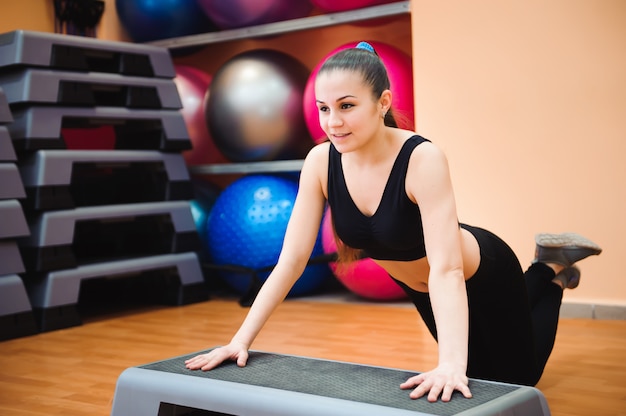 Istruttore atletico della donna che fa classe aerobica con gli stepper. sport