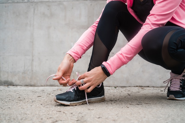 Foto donna atletica che lega i suoi laccetti.