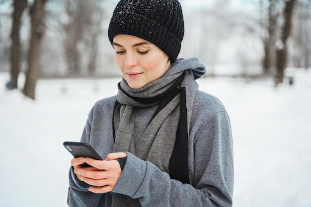 Photo athletic woman using smartphone during her winter workout in sno