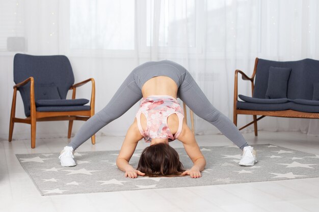 Athletic woman with her legs wide apart bends upside down