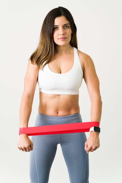 Athletic woman with a resistance band. Portrait of a fit and slim young woman with strong abs holding a fitness band to exercise the muscles of her chest