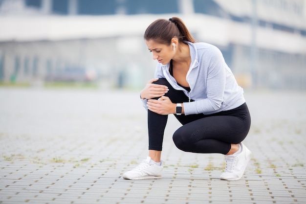 Athletic women holding knee having a trauma