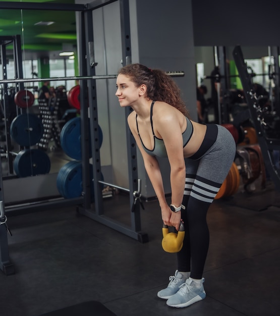 ジムでケトルベルで運動をしている運動の若いフィットの女性。フリーウェイト、ファンクショナルトレーニング